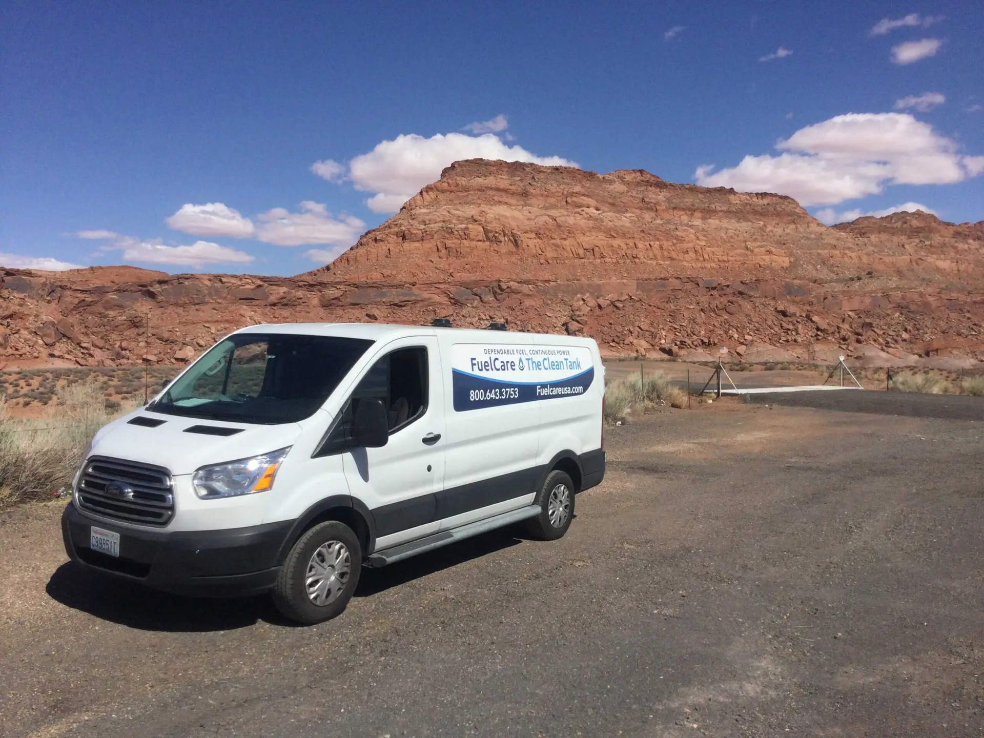 White van parked by stunning red rock formation, inviting exploration of desert beauty.