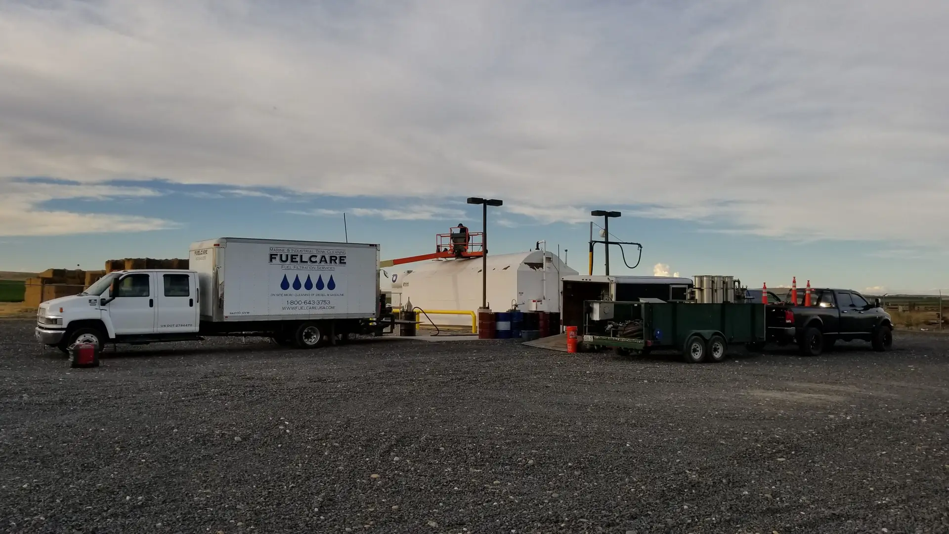 Utility trailer and police truck at a remote worksite with a maintenance crew on the roof.