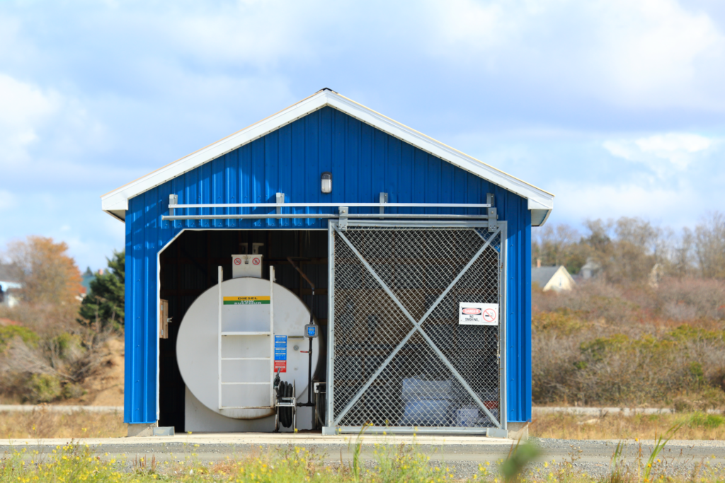 Blue shed with diesel fuel tank in a rural setting, emphasizing safety and functionality.
